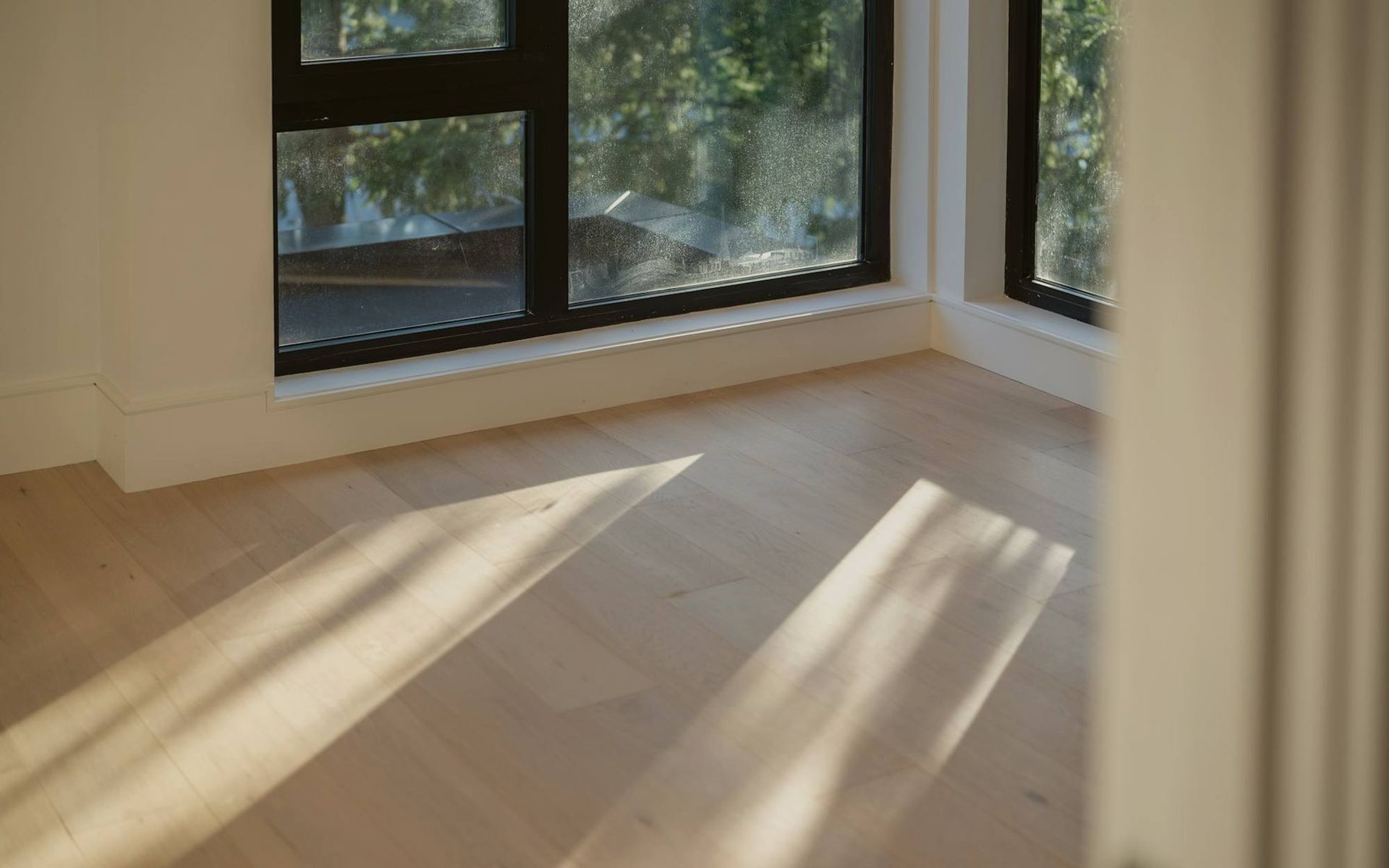 Late sun across a white oak floor along a window wall